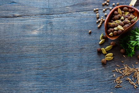 Mix pepper in vintage scoop, herbs and spices over dark wooden background with space for text. Cooking ingredients.の写真素材