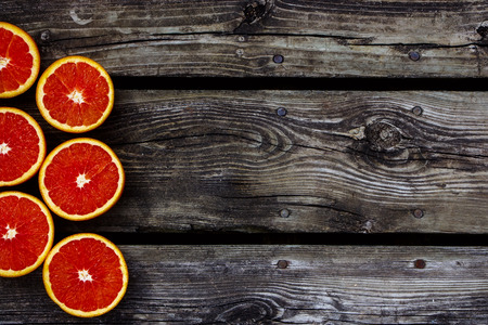 Top view of organic oranges halves fruits on rustic wooden background with space for text.の写真素材