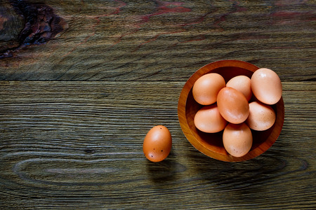 Wooden bowl with eggs over rustic texture. Food background with space for text.の写真素材