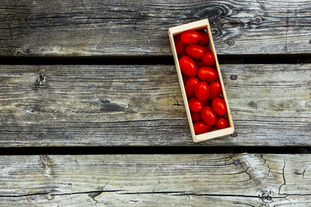 Wooden box with fresh tomatoes on vintage texture with space for text.の写真素材