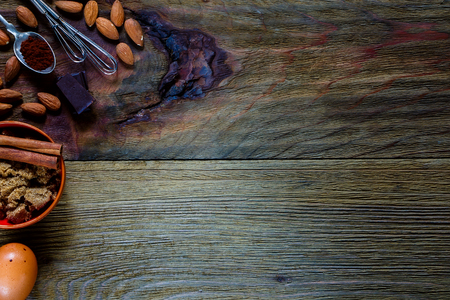 Ingredients for baking (eggs, brown sugar, almonds, cacao) over rustic wooden background with space for text. Top view. Food or cooking concept.の写真素材