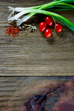 Fresh tomatoes, green onion and spices on rustic wooden background with space for text. Vegetarian food, health or cooking concept.の写真素材