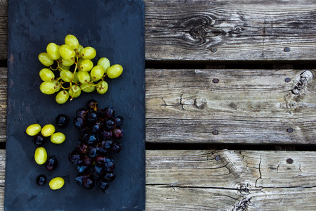 Fresh Grapes on vintage wooden and slate texture. Space for text. Food background.の写真素材