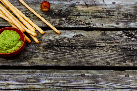 Bread sticks and guacamole dip over rustic wooden background with space for text. Healthy snack. Food concept.の写真素材
