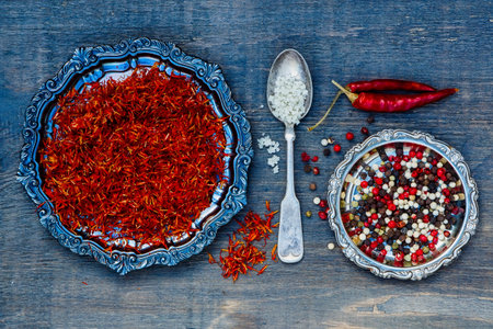 Saffron, grey salt and peppercorn mix on dark wooden background.