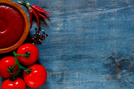 Tomato sauce with fresh ingredients on dark wooden background with space for text. Top view.の写真素材