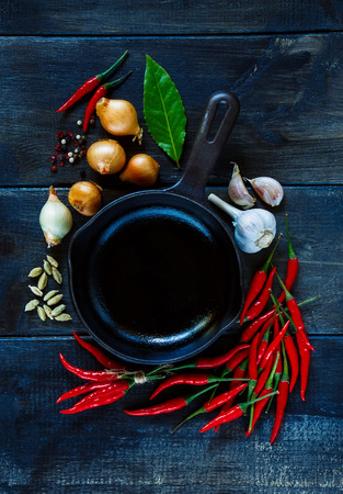 Hot red peppers, garlic, onion with spices and herbs for use as cooking ingredients on dark wooden background.の写真素材