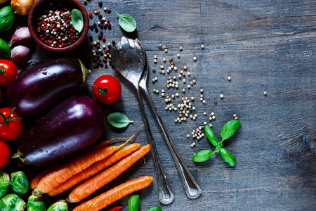 Healthy cooking ingredients with fresh vegetables, aromatic herbs and spices on dark wooden background. Vegetarian food, diet, health or cooking concept. Top view.の写真素材
