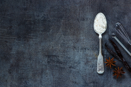 Whole flour in vintage spoon and aromatic spices for baking on dark metal background with space for text.. Christmas and holidays concept. Top view. Healthy food ingredients.の写真素材