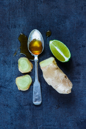 Background with honey in vintage spoon, lemon and ginger. Health concept. Dark rustic style. Top view.の写真素材