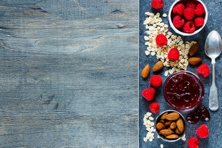 Healthy food. Ingredients (muesli, nuts, fresh berries and fruity jam) for delicious breakfast on...