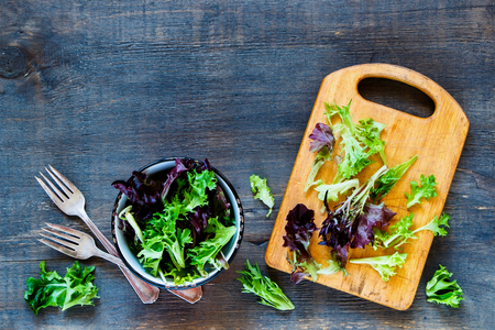 Healthy salad in vintage bowl over rustic wooden background, top view, copy space.の写真素材