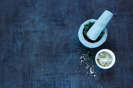 Spices selection. Mortar and pestle with red peppercorns and thyme on grunge background with space for text, top view.の写真素材