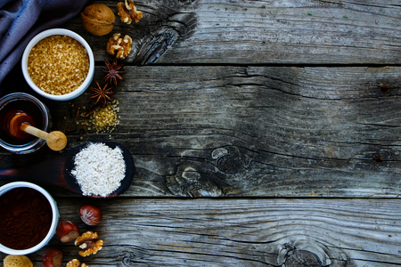 Top view of ingredients for making cake. Cocoa powder, spices, flour, eggs, sugar, honey and nuts on old rustic wooden background, copy space, horizontal compositionの写真素材