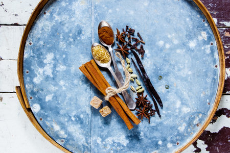 Top view of colourful and bright assortement of spices on old rusty iron background over white...