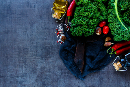 Colorful raw vegetable ingredients for healthy cooking or salad making with kale, olive oil and tomatoes on vintage backdrop, top view, copy space. Diet or vegetarian food concept, horizontal compositionの写真素材