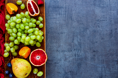 Various colorful fruit selection on rustic wooden chopping board over slate background, top view. Agriculture, Gardening, Harvest Concept. Detox, dieting, clean eating, vegan, fitness, healthy lifestyle conceptの写真素材