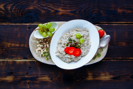 Delicious Homemade oatmeal porridge with berries and seeds in bowl on dark rustic background.の写真素材