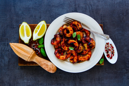 Grilled prawns in white plate with lemon, soy sauce and spices on wooden board .の写真素材