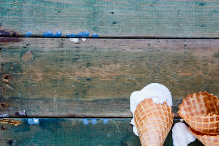 Top view of melting scoops caramel ice cream in waffle cone over grunge wooden background, copy space.の写真素材
