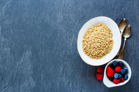 Breakfast set on stone table. Rice cereal with frozen berries over grey slate backdrop, top view, copy space, horizontalの写真素材