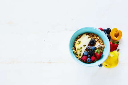 Rustic white vintage breakfast table with bowl of homemade granola, fresh berries and fruits on grunge background, copy space. Flat lay style. Healthy breakfast conceptの写真素材