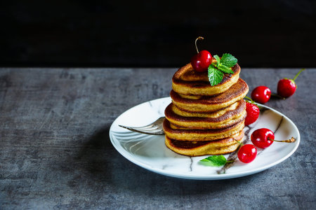 American breakfast. Stack of pancakes topped with berries and mint leaves on wooden background, selective focus. Copy spaceの写真素材