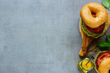 Two vegan sandwiches made of fresh bagel, quinoa, tomato and avocado sauce on chopping board over grey stone background, top view. Clean eating, detox, vegan, vegetarian food conceptの写真素材