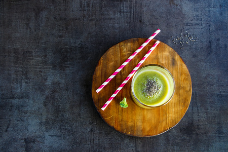 Glass jar filled with fresh green smoothie on wooden board over concrete table. Green healthy food, vegetarian, clean eating concept. Top view, copyspaceの写真素材