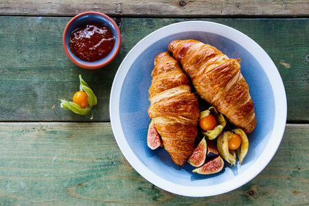 Top view of breakfast table with croissants, apricot jam and fresh ripe fruit on old wooden background, copy space. の写真素材