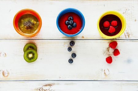 Flat lay of various colorful smoothies jars with berries and fruits on white wooden board. Healthy breakfast, vegetarian or raw eating concept. Flat-lay, top viewの写真素材