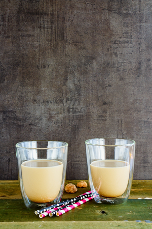 Cold ice coffee or latte in glass cups on old wooden board, copy space. Dark concrete wall baclground.の写真素材
