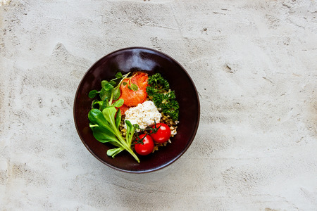 Rainbow power buddha bowl. Quinoa, smoked salmon, ricotta cheese and fresh vegetables on light concrete background. Clean eating, healthy lifestyle. Top view, flat lay.の写真素材