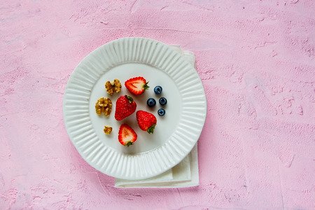 Walnut with fresh ripe strawberry and bluebbery on pink background. Natural organic food style top view flat layの写真素材