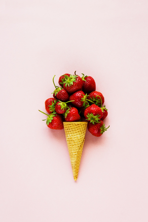 Spring or summer composition. Flat-lay of waffle sweet cone with fresh strawberry on pastel light pink background. Holiday mood concept. Top view.の写真素材