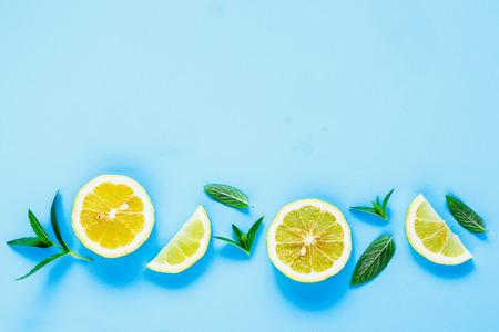 Creative layout made of fresh lemon slices and mint leaves. Ingredients for summer cocktail and lemonade on pastel blue background top view. Flat lay styleの写真素材