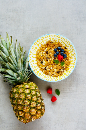 Healthy breakfast flat lay. Delicious granola bowl, pineapple and fresh berries top view. Superfood and detox concept.の写真素材