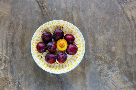 Fresh garden plums in bowl flat lay