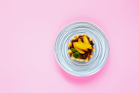 Waffle with chocolate and peach on pink background flat layの写真素材