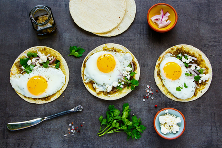 Flat lay of corn tortillas with fried eggs, pesto sauce and feta cheeseの写真素材