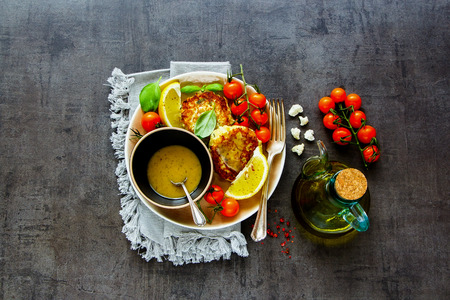 Flat-lay of vegetarian cauliflower cakes with sauce and fresh vegetables top viewの写真素材