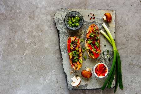 Hot mushroom toasts with grilled bell pepper on stone board captured from above, flat layの写真素材