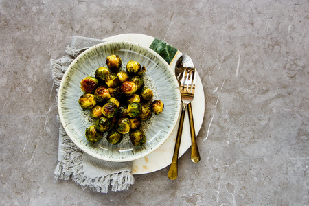 Fried Brussels sprouts in plate over grey concrete table background flat layの写真素材
