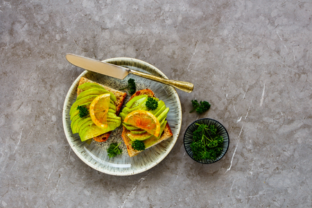 Flat-lay of vegan avocado toasts with lemon and parsley in plateの写真素材