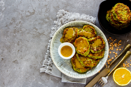 Flat lay of healthy oat and zucchini pancakes with dressing in plate over vintage concrete backgroundの写真素材