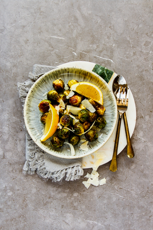 Fried Brussels sprouts with parmesan cheese in plate over rustic concrete background flat layの写真素材