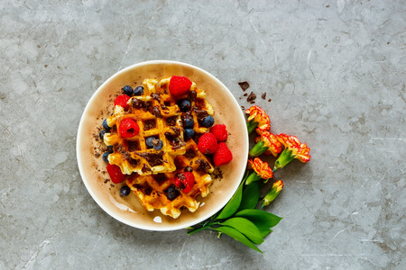 Belgian waffles with berries and chocolate in plate captured from above, flat layの写真素材