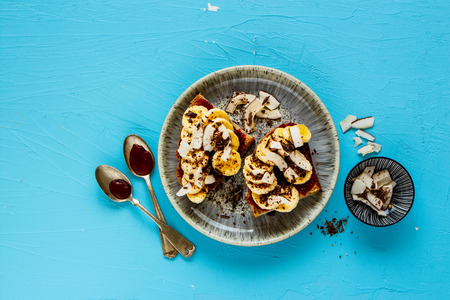 Delicious banana coconut chocolate toast on blue background, healthy snack flat lay top viewの写真素材