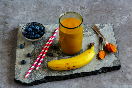 Jar of mango banana turmeric smoothie on stone board の写真素材