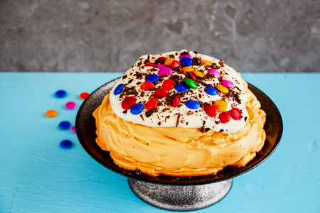 Close up of Meringue cake Pavlova with colorful Sprinkles, whipped cream and chocolate on cake standの写真素材